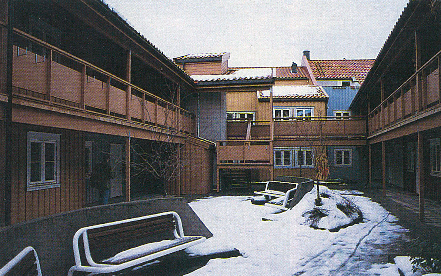 Indre kvartal på Bakklandet, Trondheim 1992. Arkitekt: Odd Thommesen AS. En mellomform mellom atriumhus og bygård. Ved å slå sammen flere parseller dannes et større gårdsrom med bedre lysforhold, og svalgangsatkomst i 2. etasje gir dessuten overdekket atkomst til boliger på bakkeplan. For å styrke det sosiale miljø er det viktig at alle innganger er lagt til tunet, og at kjøkken og andre aktive rom henvender seg til fellesrommet. En tradisjonell husform med bratt saltak gjør det mulig å utnytte loftsrommet til en utvidelse av boligene i 2. etasje. (Foto: TB)
