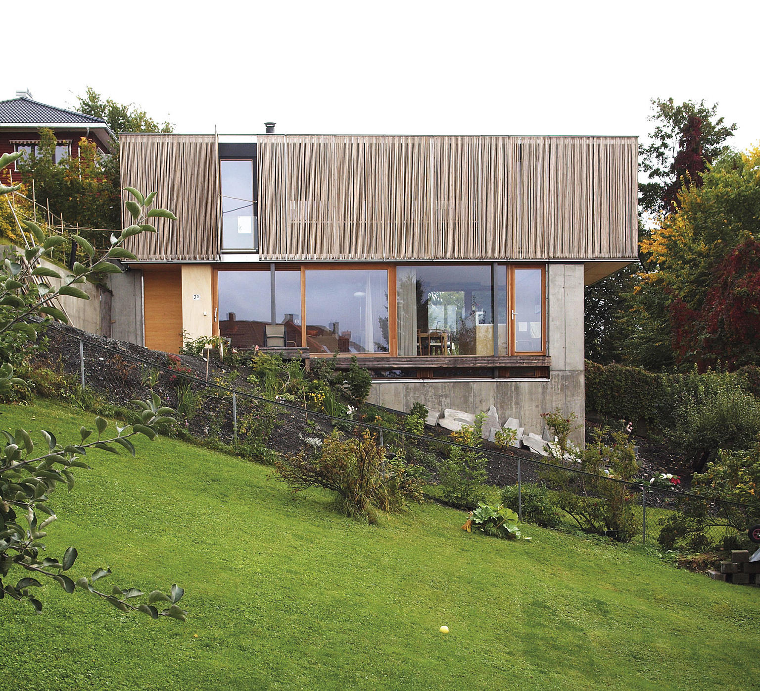 Forstøtningsmurene i betong danner husets nedre etasje. Over denne ligger en trekonstruksjon.