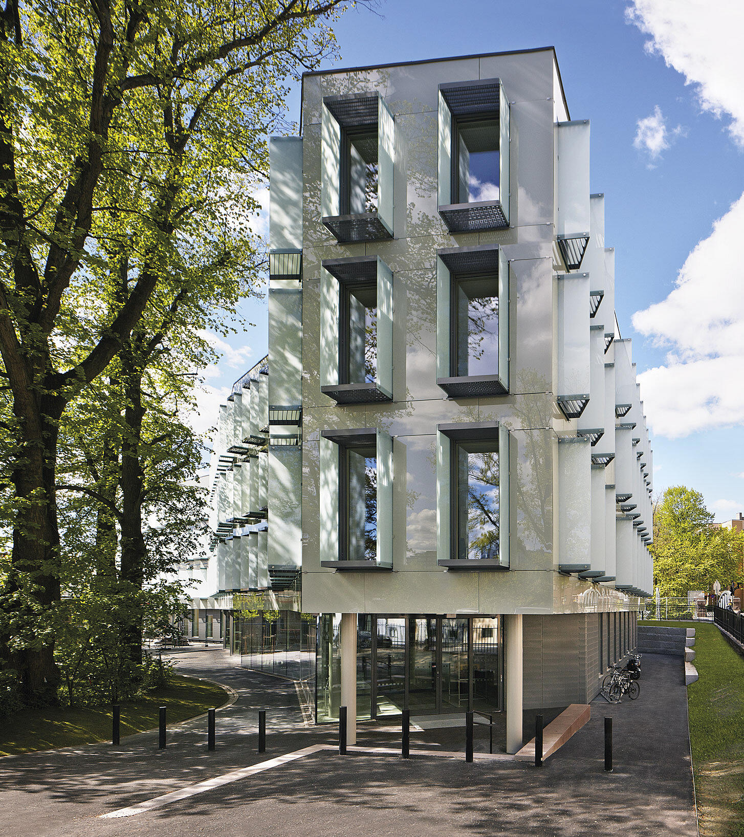Bygningen følger den buede trerekken. Above: The sunshading is solved with externally mounted glass boxes.