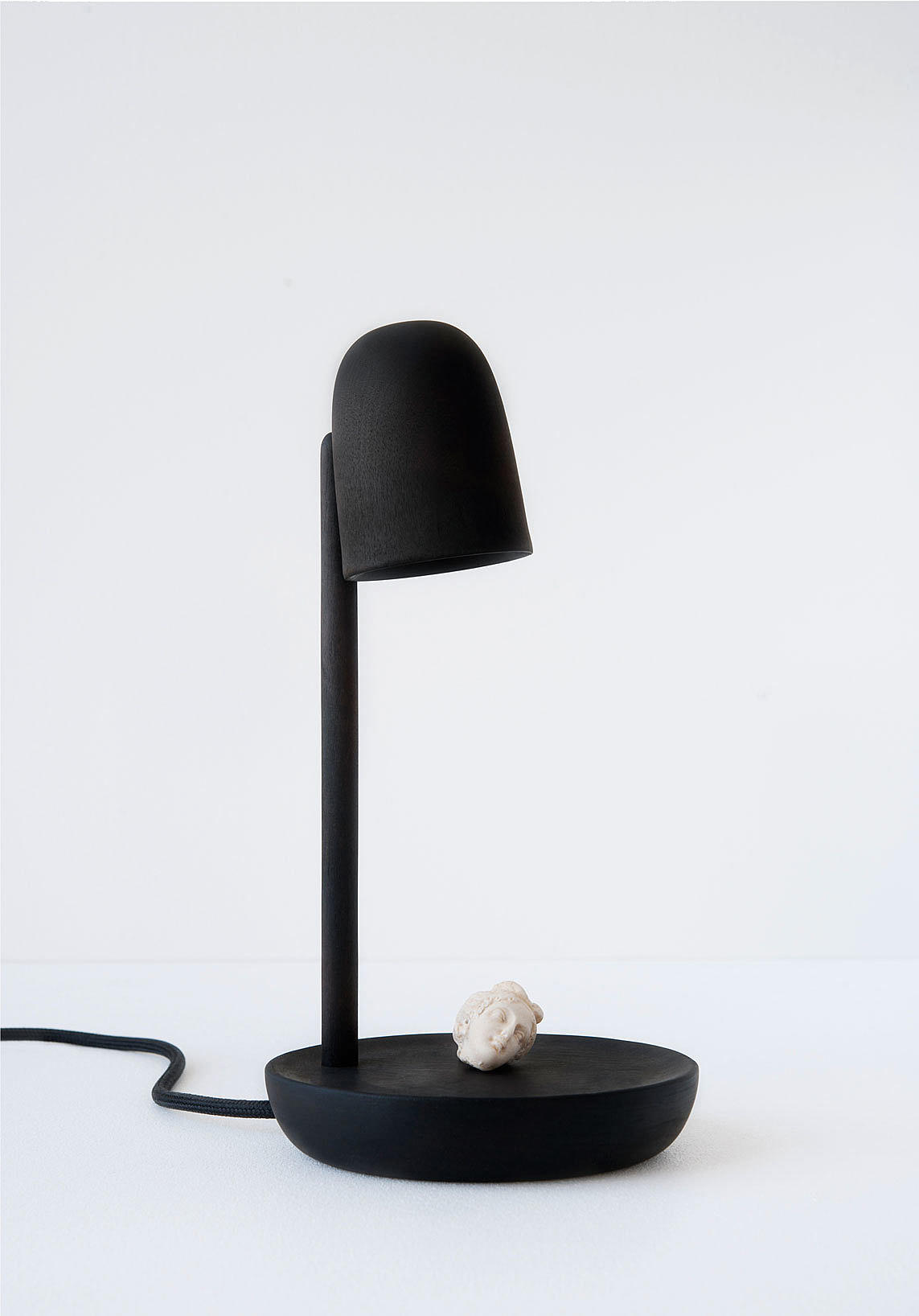 Piedistallo, lampe i bjørk med brent overflate. Lyset som fremhever det som ligger på basen (pidestall). Foto: Lasse Fløde