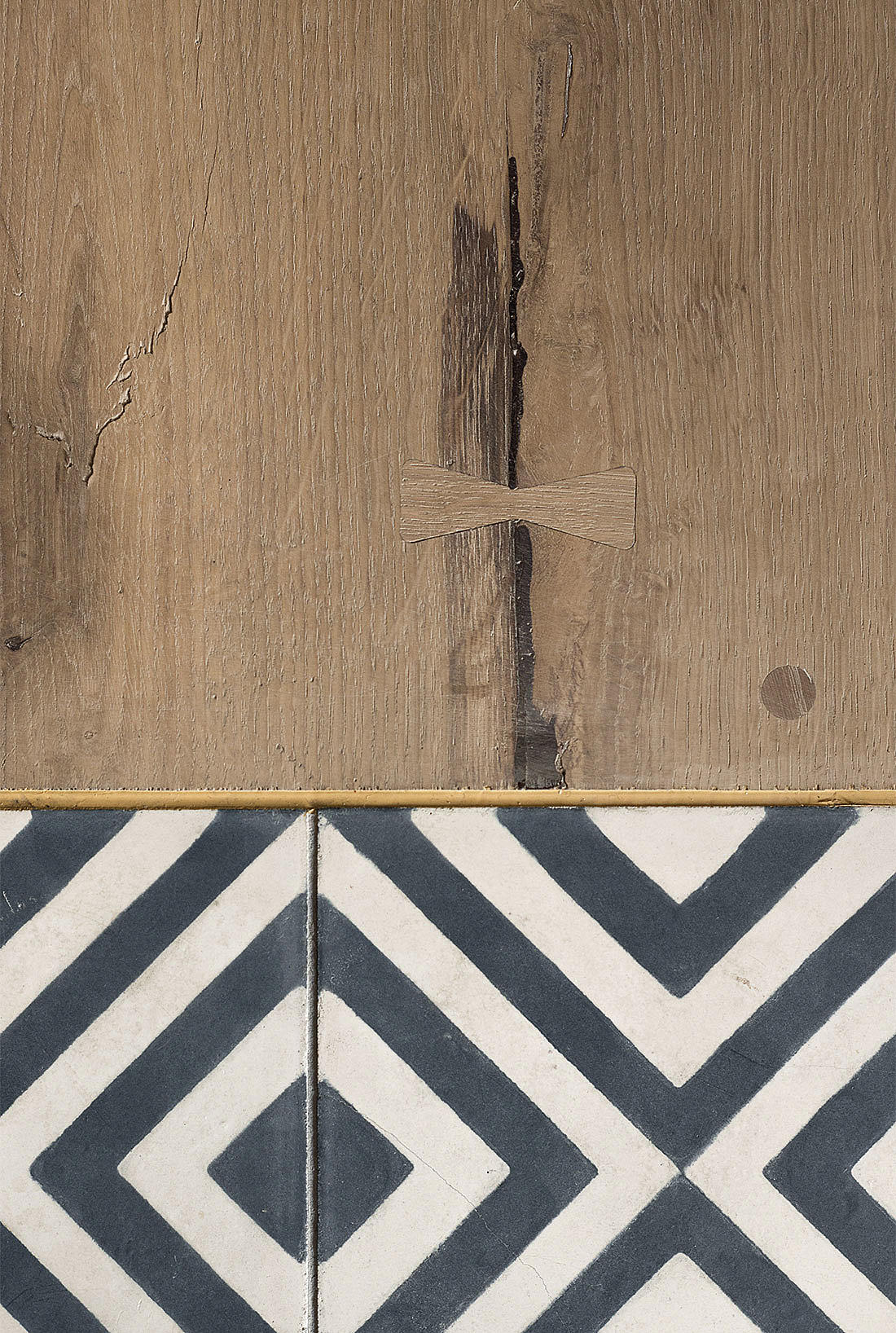 Sementfliser og eikeplank: Gulvovergangen fra ventesone til spiseareal.