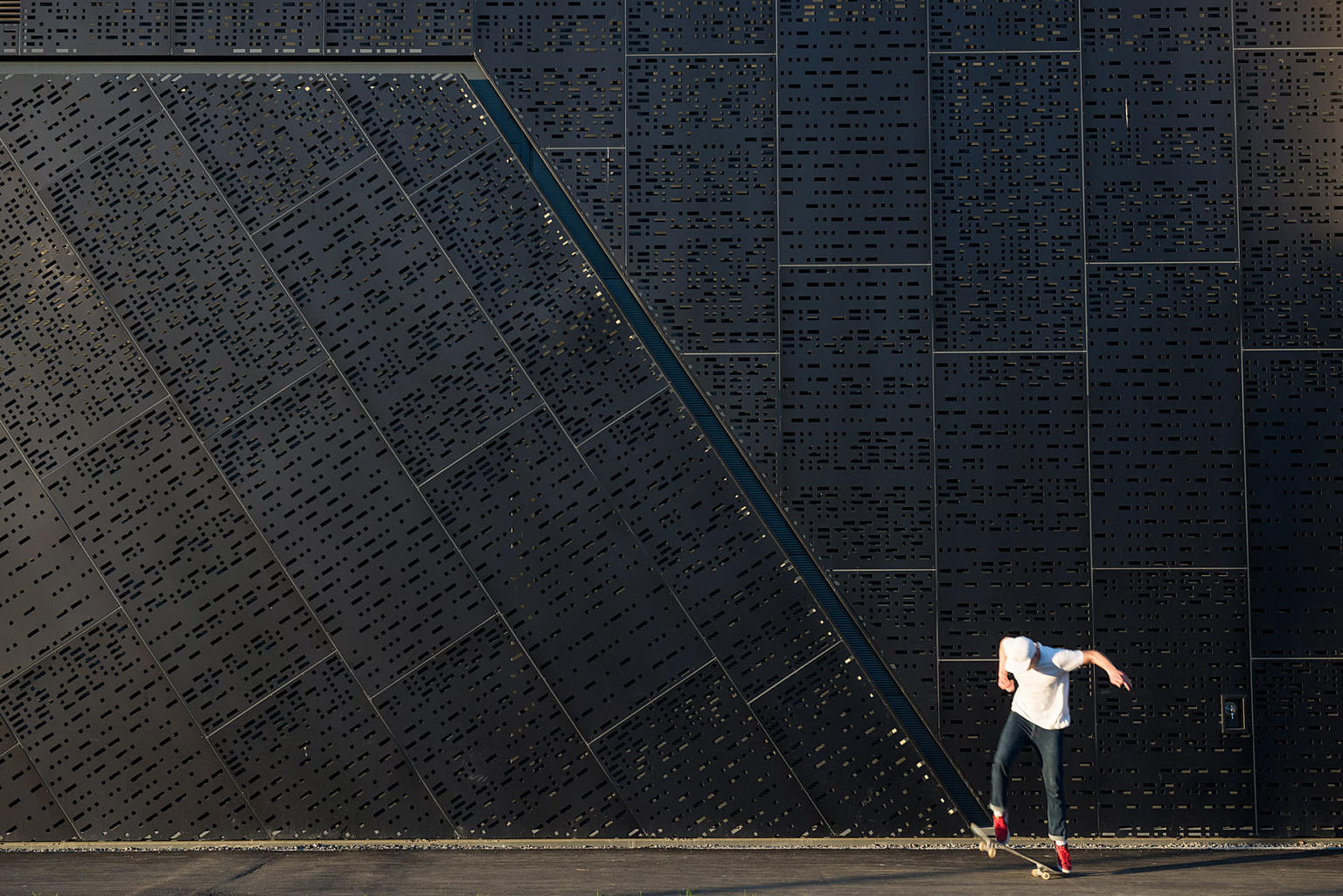 En skater ruller på uteområdet ved skatehallen.