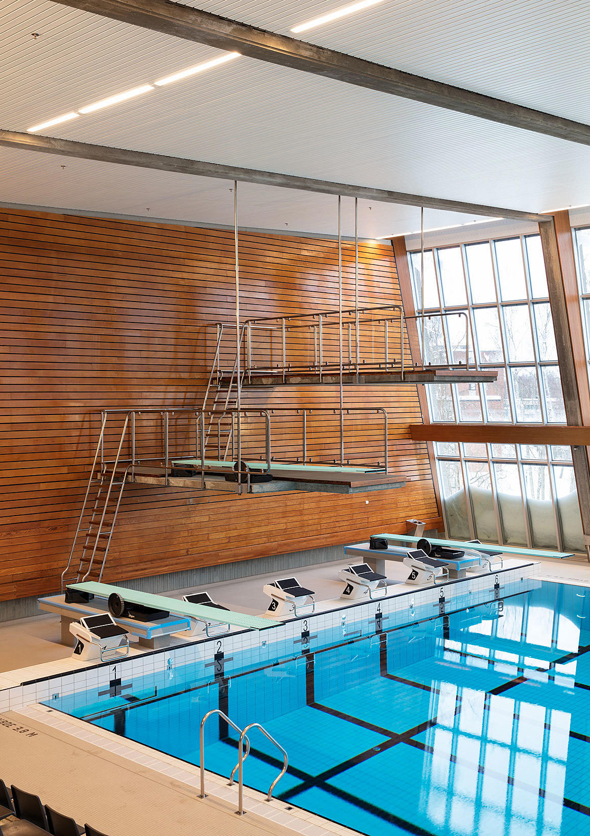 Hengende stupetårn. Den uortodokse løsningen med stupetårn som henger i stag fra taket understreker rommets åpenhet. The room is opened up by the hanging diving platforms.