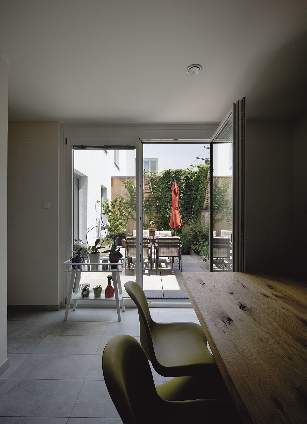 Introvert boligform. Atriumhuset med privat uterom integrert med oppholdsonen på bakkeplan. Beplantingen og klatrestativene er nøye planlagt og inngår i arkitekturens strukturelle grep.