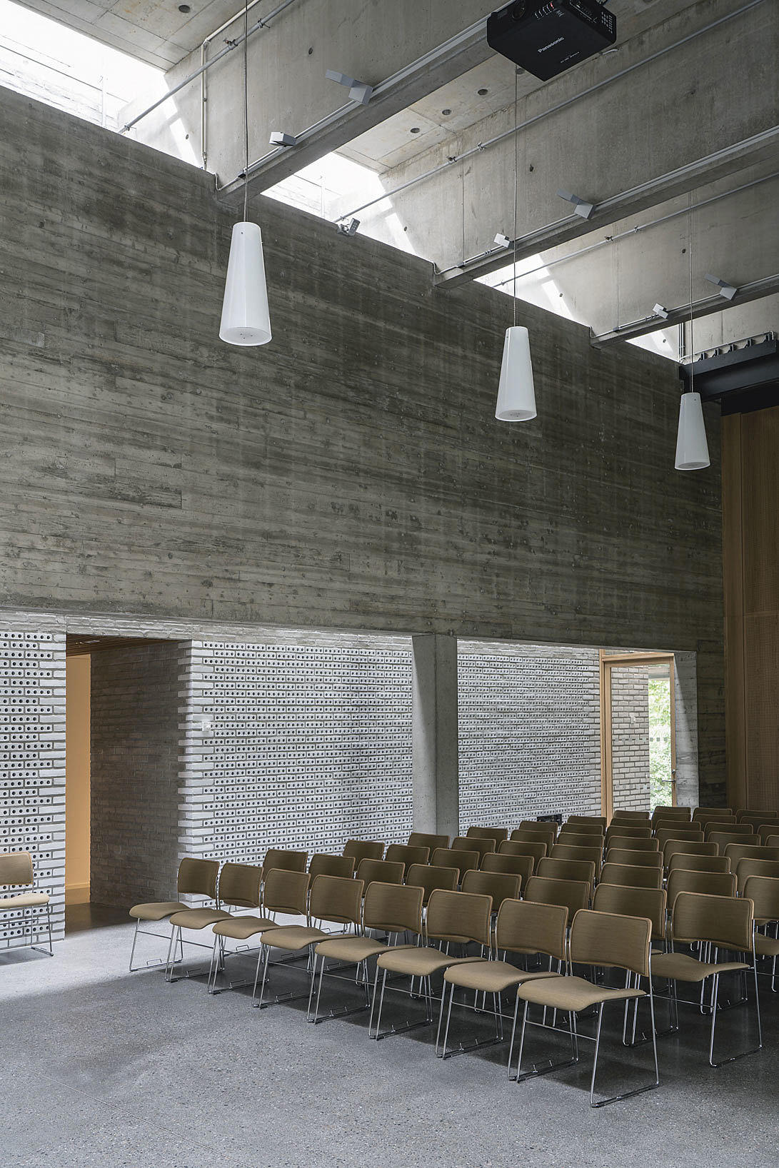 Benker og hulltegl: De langsgående betongdragerne som bærer seremonirommene skjuler tekniske føringer i etasjen over. Hullteglen har både en akustisk funksjon og huser bygningens ventilasjonssystem.