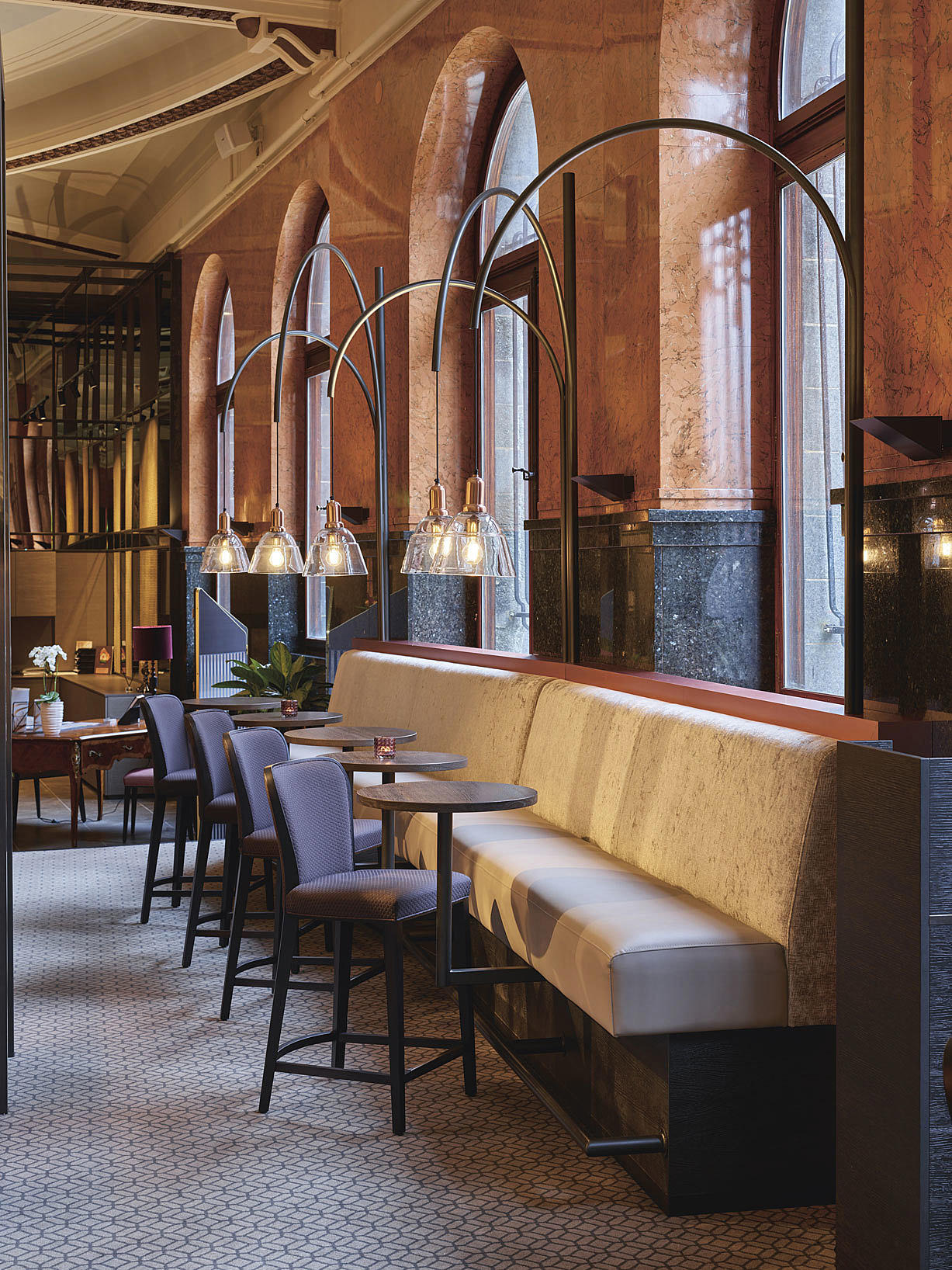 I bar-området holdes lampene av buede stålrør – et fint nikk mot jugendstilen som også er en del av de fredede elementene i byggets interiør og buen i vinduet.