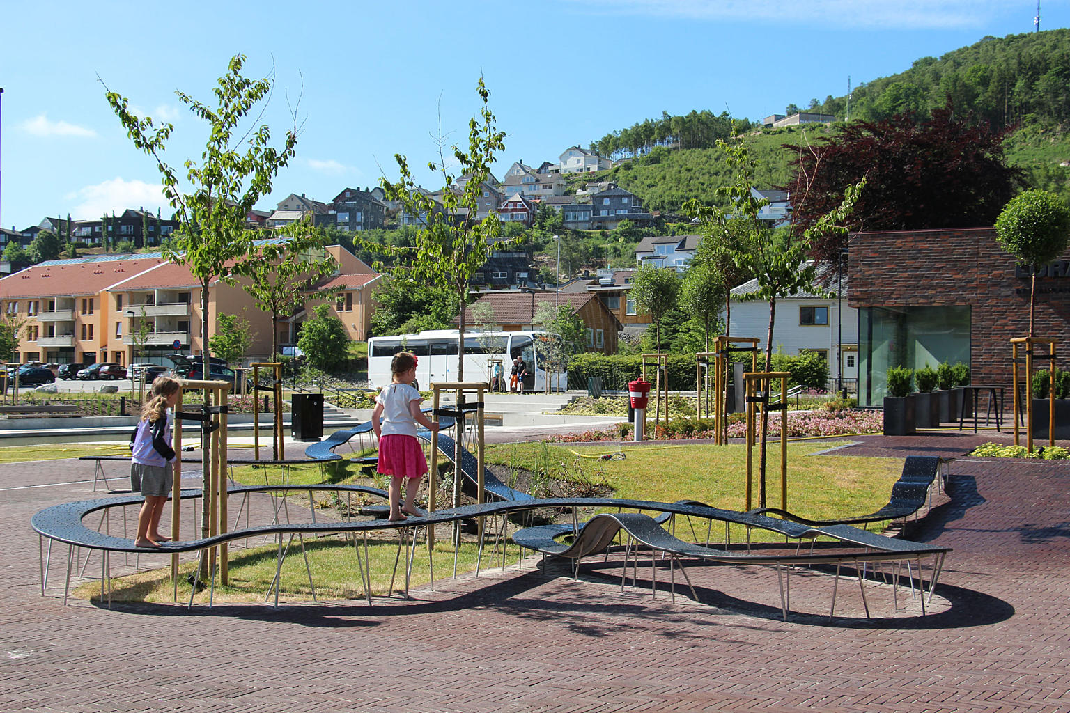 Benkene som slynger seg rundt plassen fungerer både som sittemøbel og balanserampe for store og små.