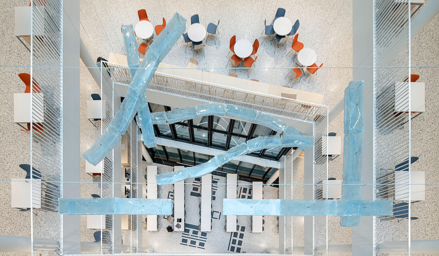 Midt i bildet ser vi ned på Tiril Hasselknippes kunstverk Queens of the Tear Duct. På gulvet under skimtes Lotte Konow Lunds verk Rettstegning. Også Marianne Heier og Steinar Haga Kristensen har bidratt til utsmykningen av huset.