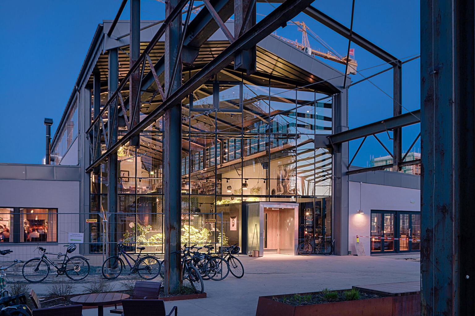 De gamle konstruksjonene og kranbanen fortsetter fra innsiden og ut i utomhusanlegget med en skrå glassvegg som klimaskille.