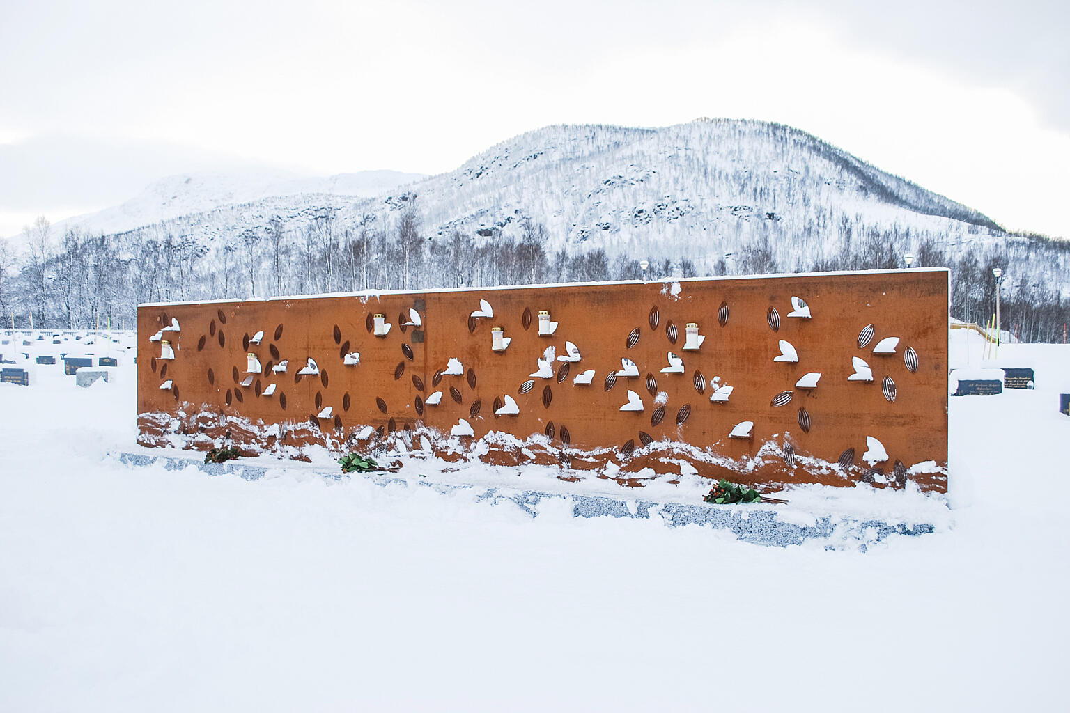 Felles minnesmerke tilrettelagt for blomster og lystenning, og med avsatt plass til navneplaketter i bladform.